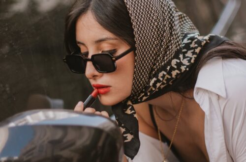 elegant woman doing makeup by the car mirror