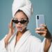 confident black female with sheet mask taking selfie on smartphone